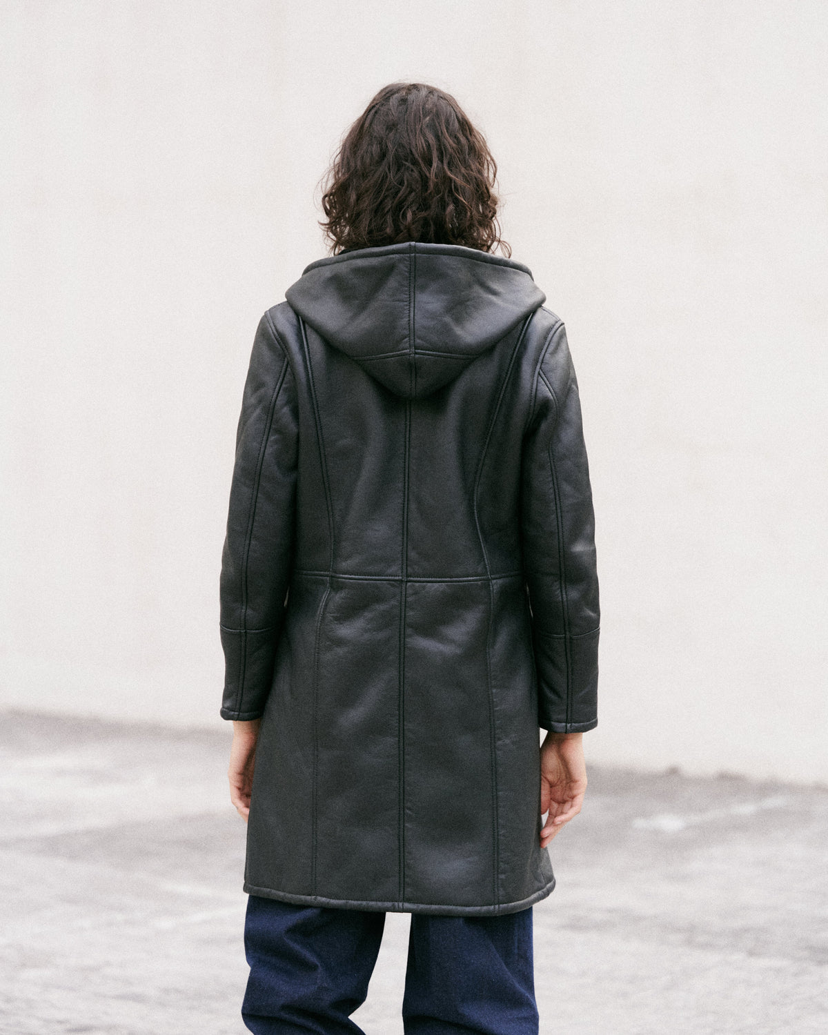 Manteau long en peau lainée noire, élégant et sophistiqué